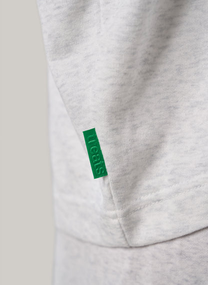 Close-up of a gray sweatshirt with a green tag on a light gray background