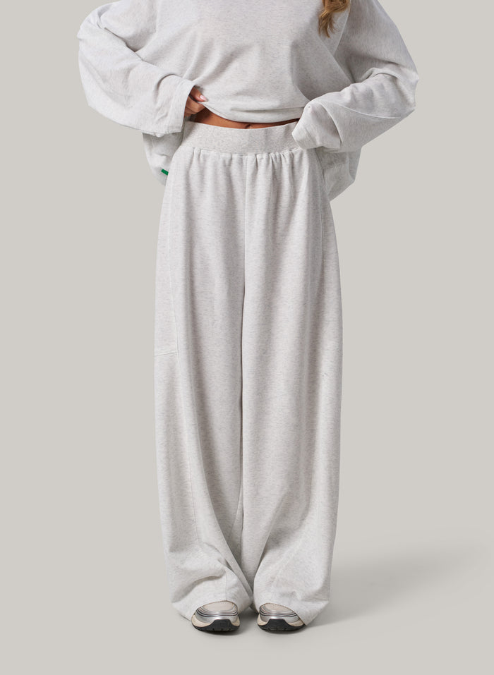 Person wearing a light grey sweatshirt and wide-leg pants on a plain background
