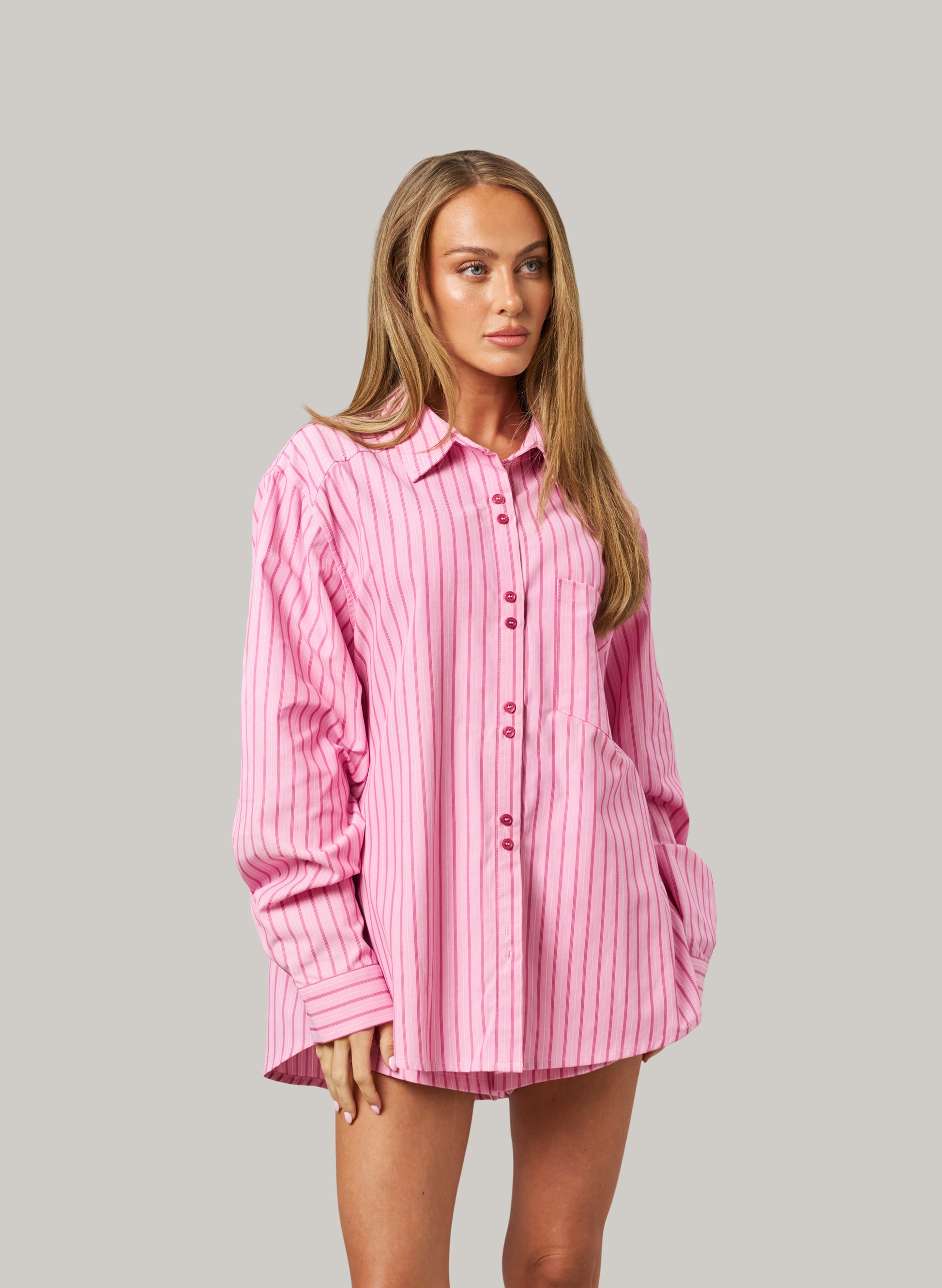 Woman wearing a pink striped set against a gray background
