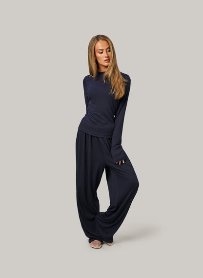 Woman wearing a navy blue outfit on a gray background