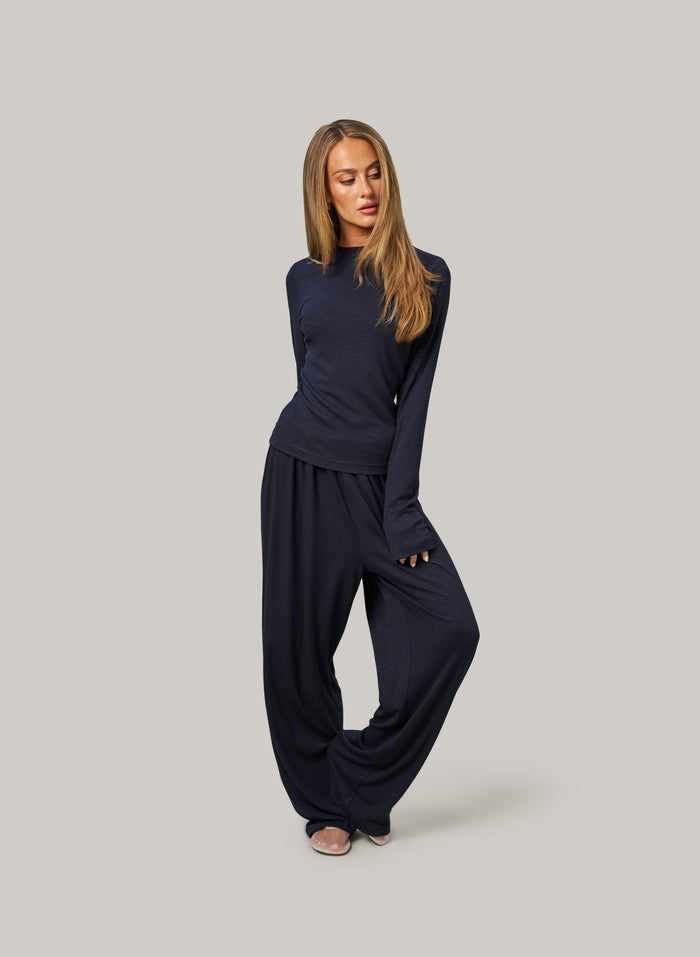 Woman wearing a navy blue outfit on a gray background
