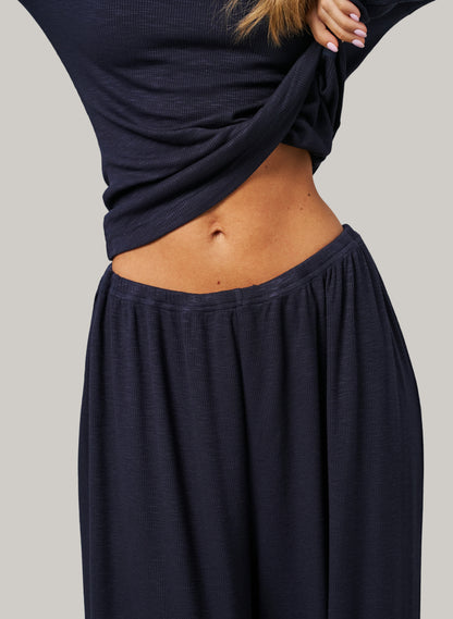 Person wearing a navy blue long-sleeve top and skirt on a plain background