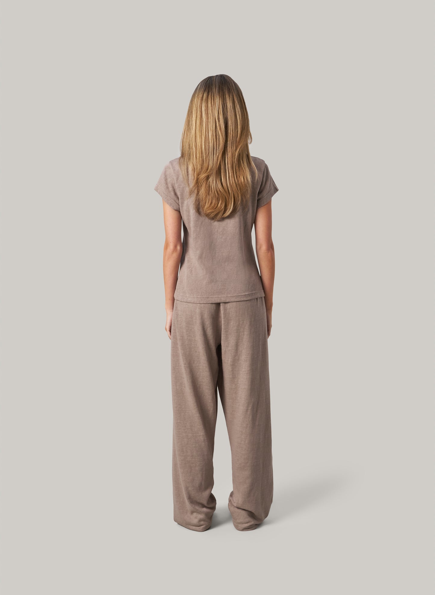 person wearing a beige background standing from behind, on light grey background