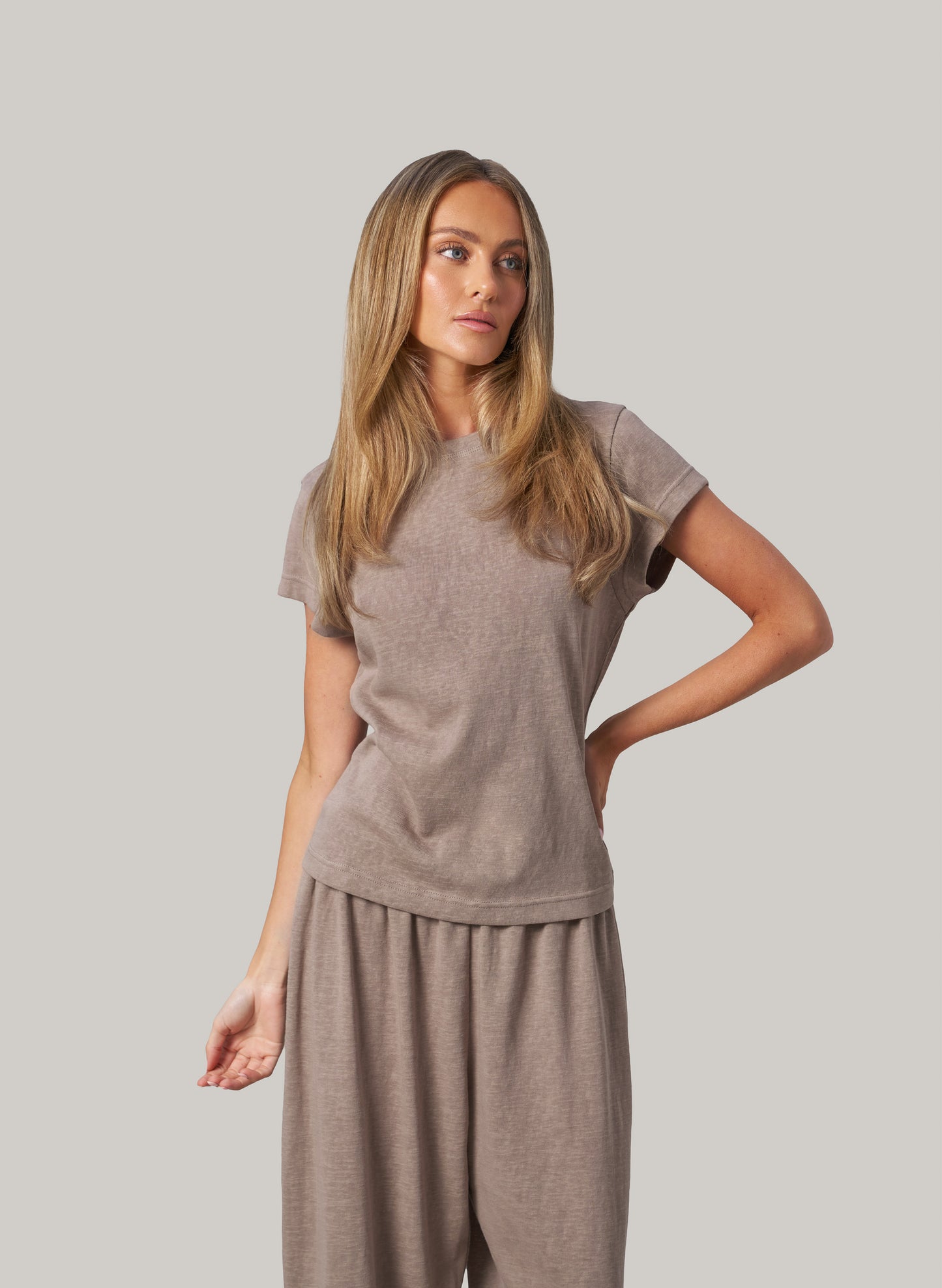 Woman wearing a beige outfit against a plain background