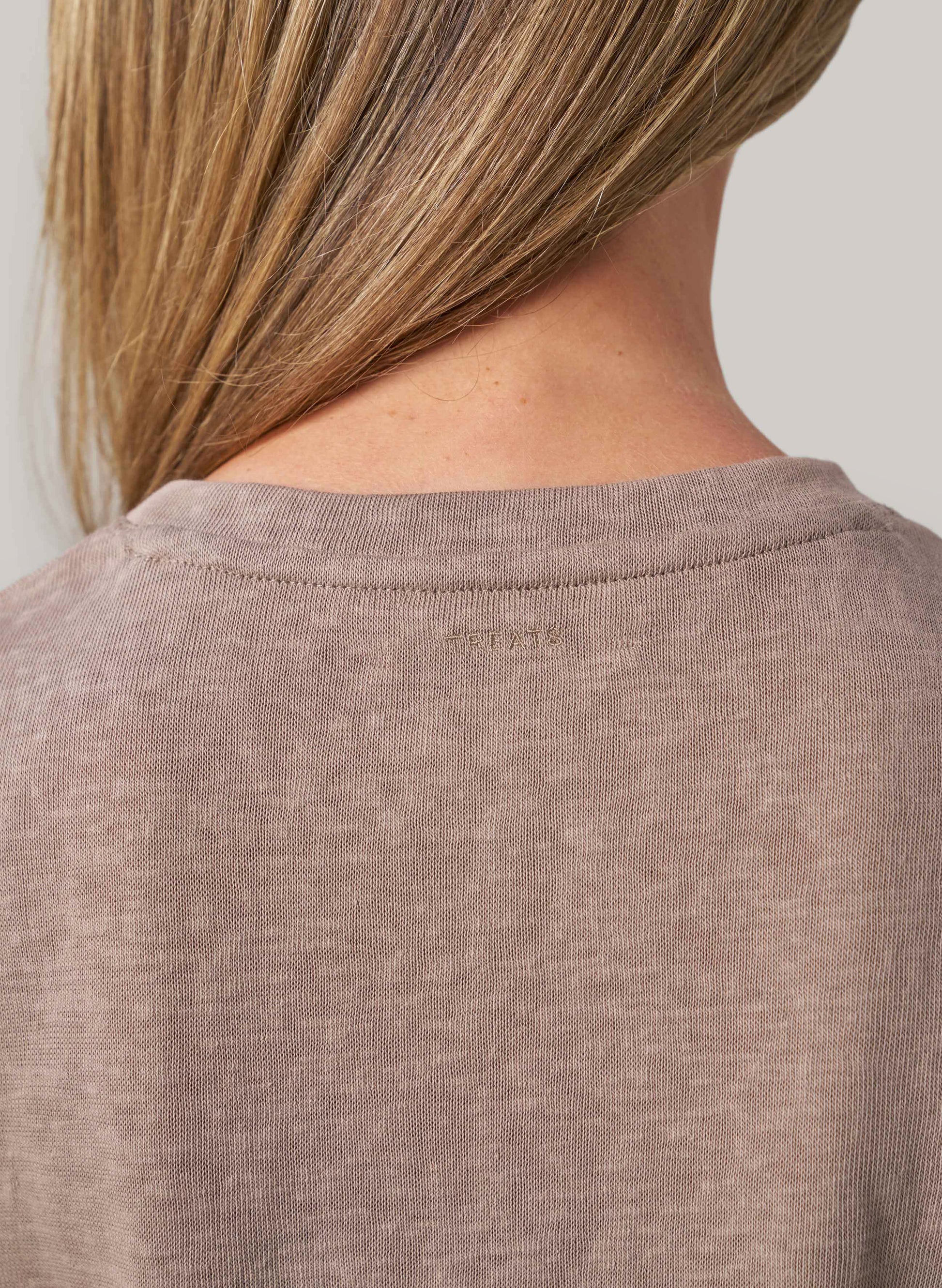 Close-up of a person wearing a beige shirt with a blurred background
