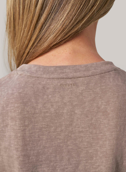 Close-up of a person wearing a beige shirt with a blurred background