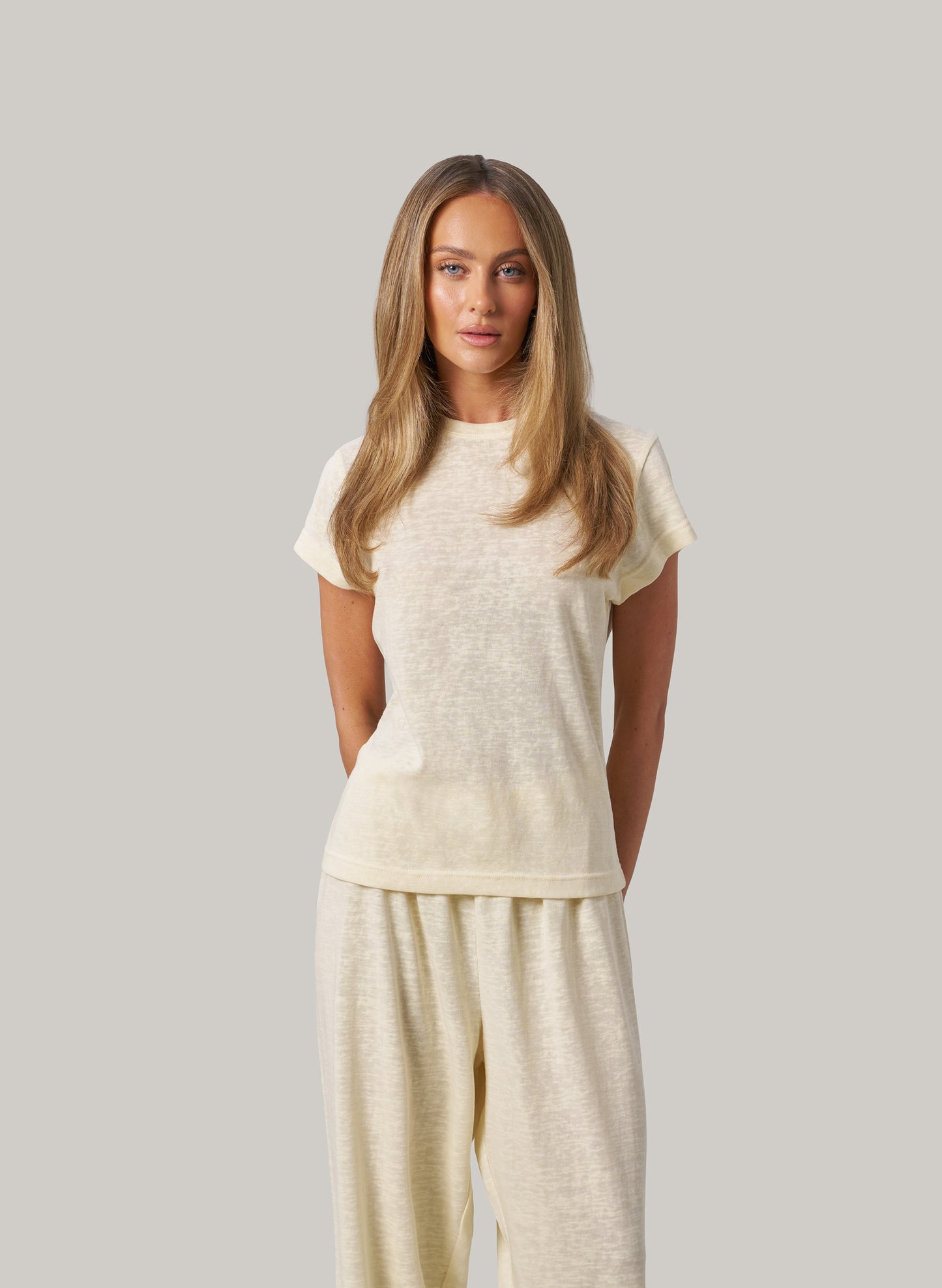 Woman wearing a butter colour outfit against a plain background