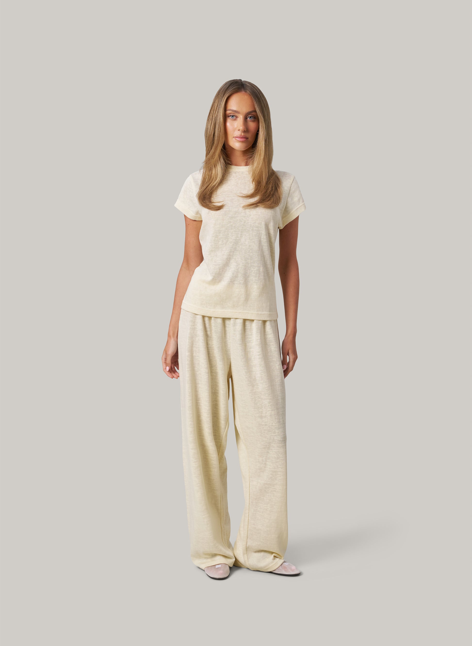 Woman wearing a butter colour outfit on a plain background