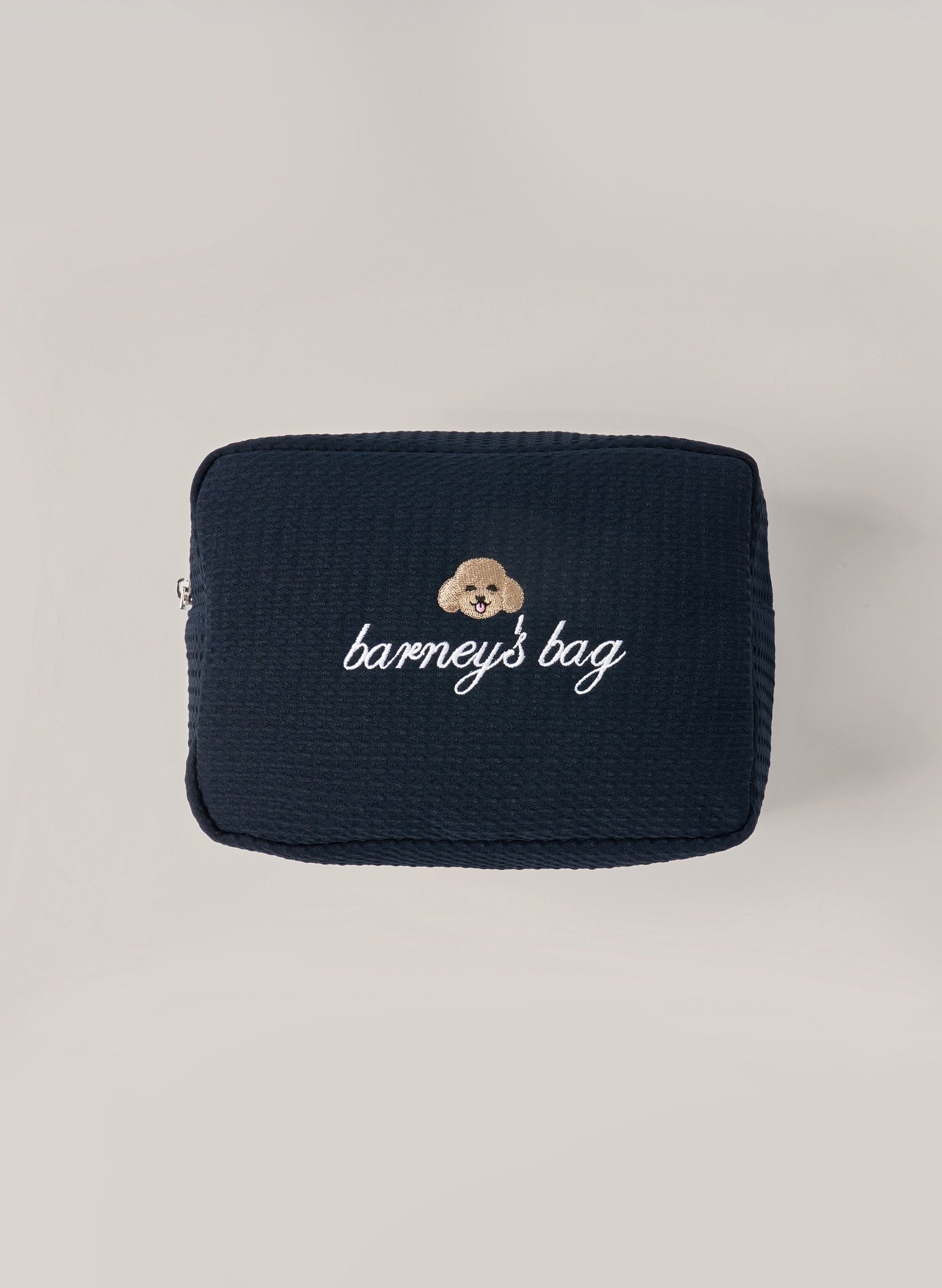 Navy waffle-textured pouch with zipper closure, featuring a dog face embroidery and ‘barney’s bag’ text on the front