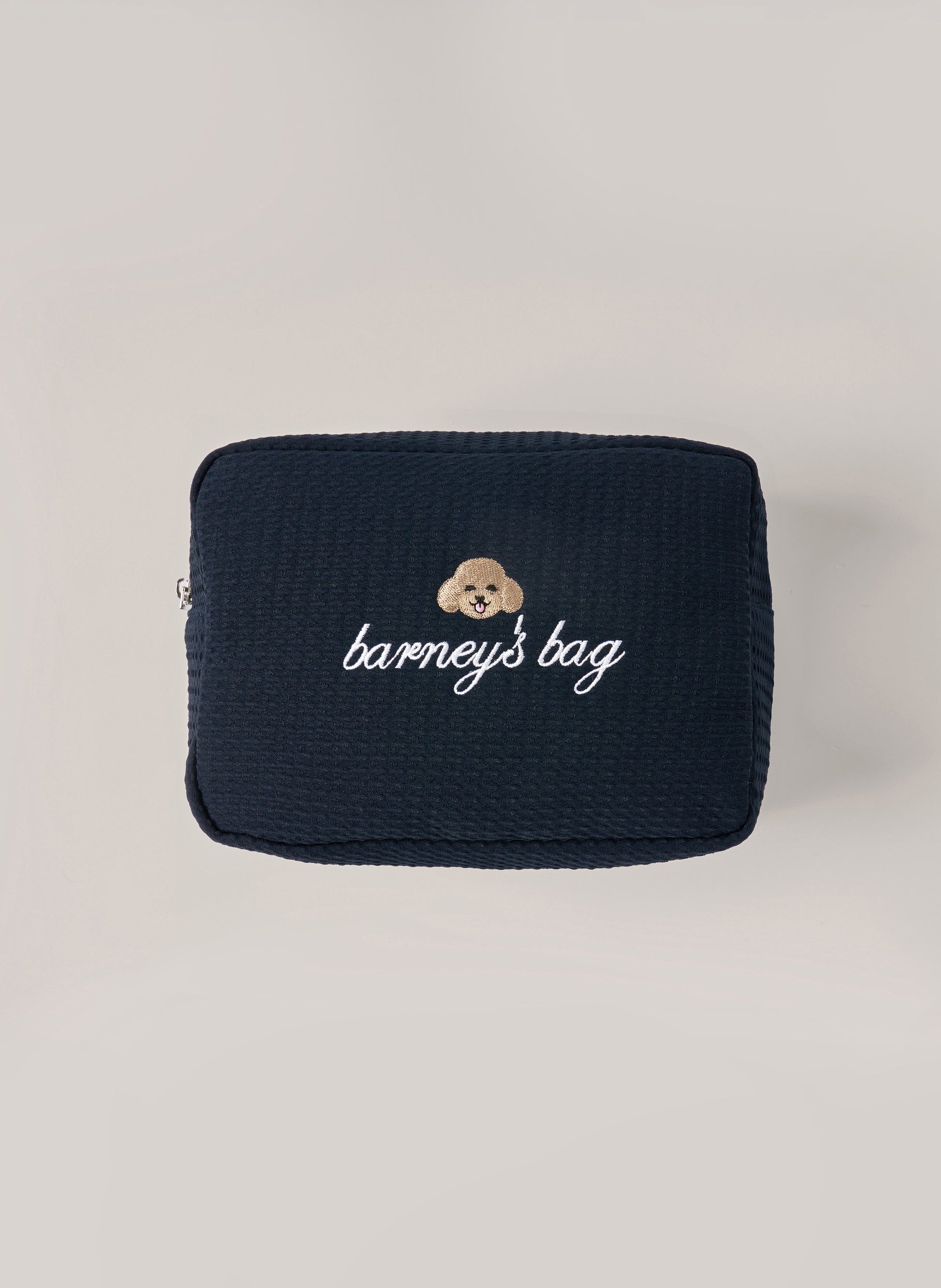 Navy waffle-textured pouch with zipper closure, featuring a dog face embroidery and ‘barney’s bag’ text on the front