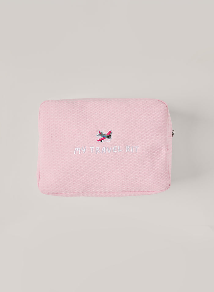 Light pink waffle-textured pouch with zipper closure, featuring an embroidered airplane and ‘my travel kit’ text on the front