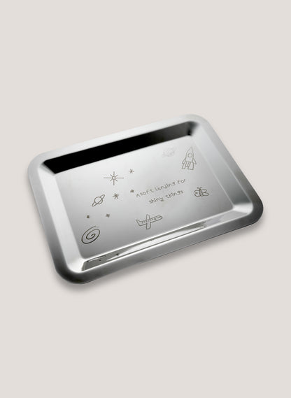 Metallic tray with engraved designs on a light gray background