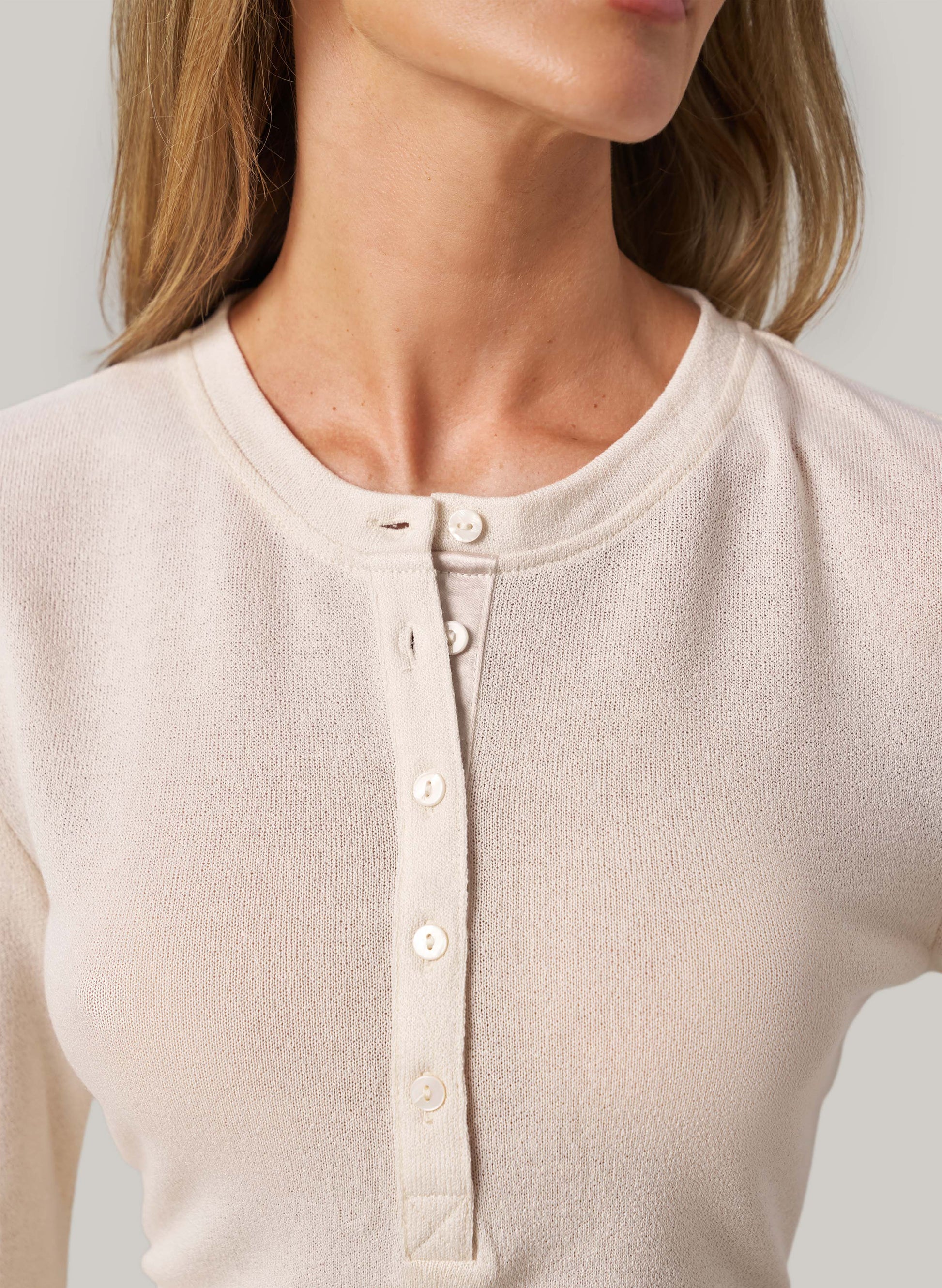 Close-up of a cream long-sleeve shirt with buttons on a plain background