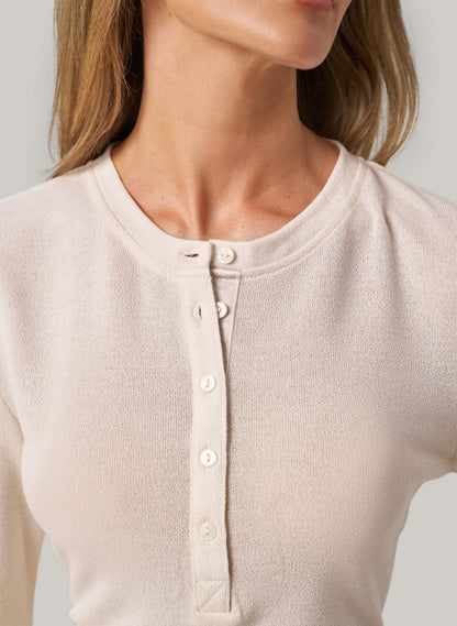 Close-up of a cream long-sleeve shirt with buttons on a plain background