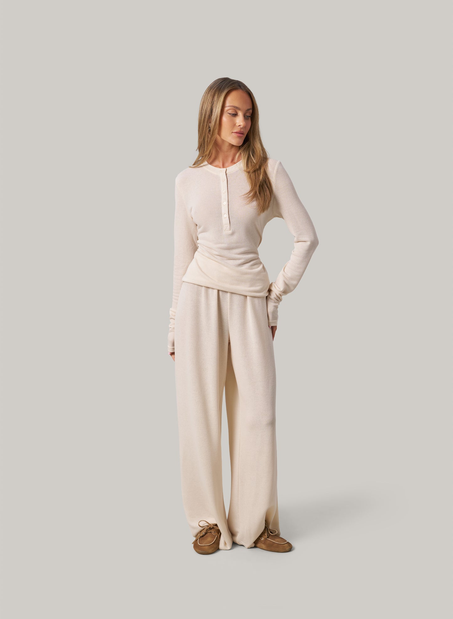 Woman wearing a cream outfit on a plain background