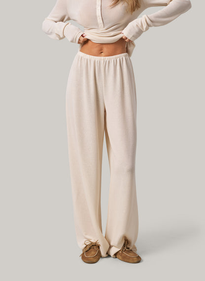 Person wearing cream pants and a matching top on a plain background