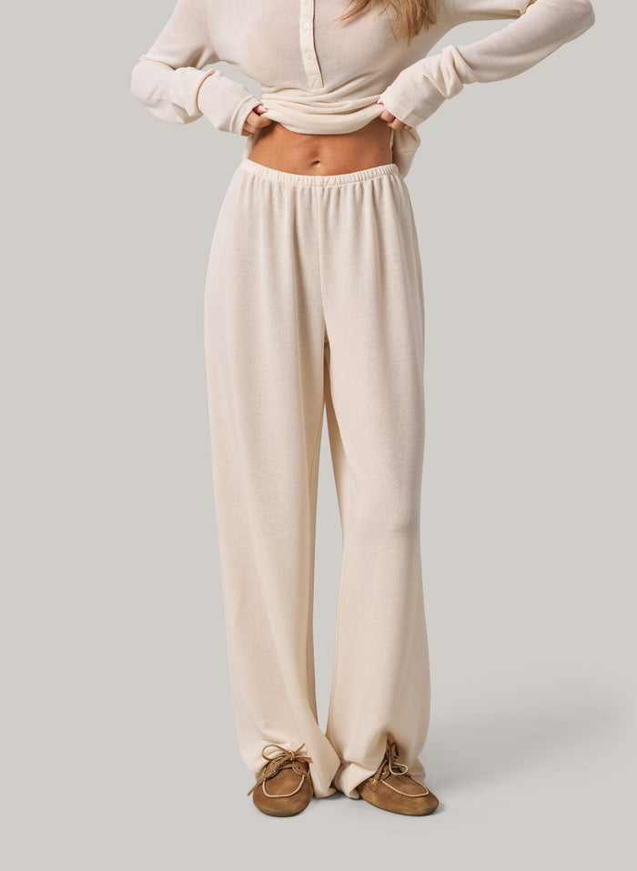 Person wearing cream pants and a matching top on a plain background