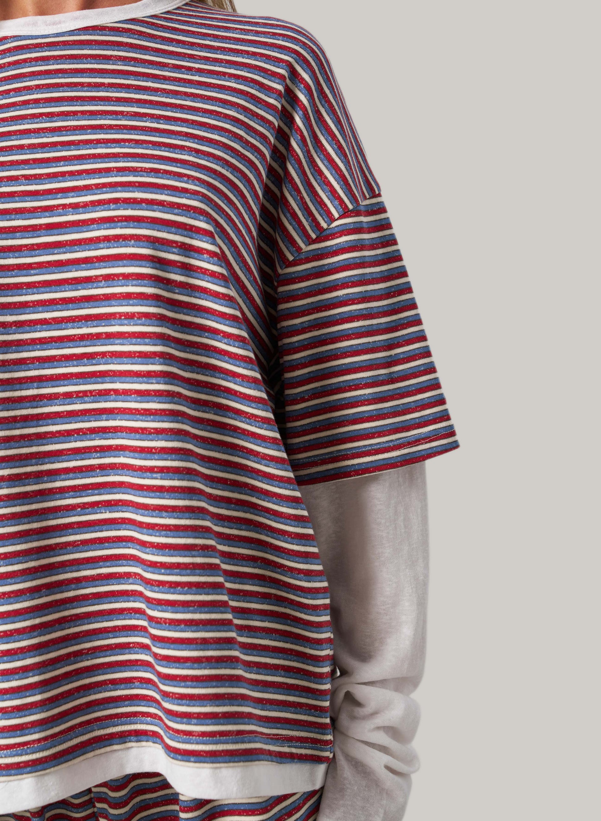Close-up of a person wearing a red, white, and blue striped shirt with a neutral background