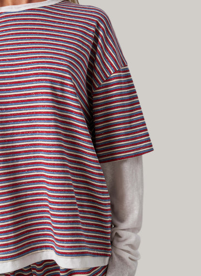 Close-up of a person wearing a red, white, and blue striped shirt with a neutral background
