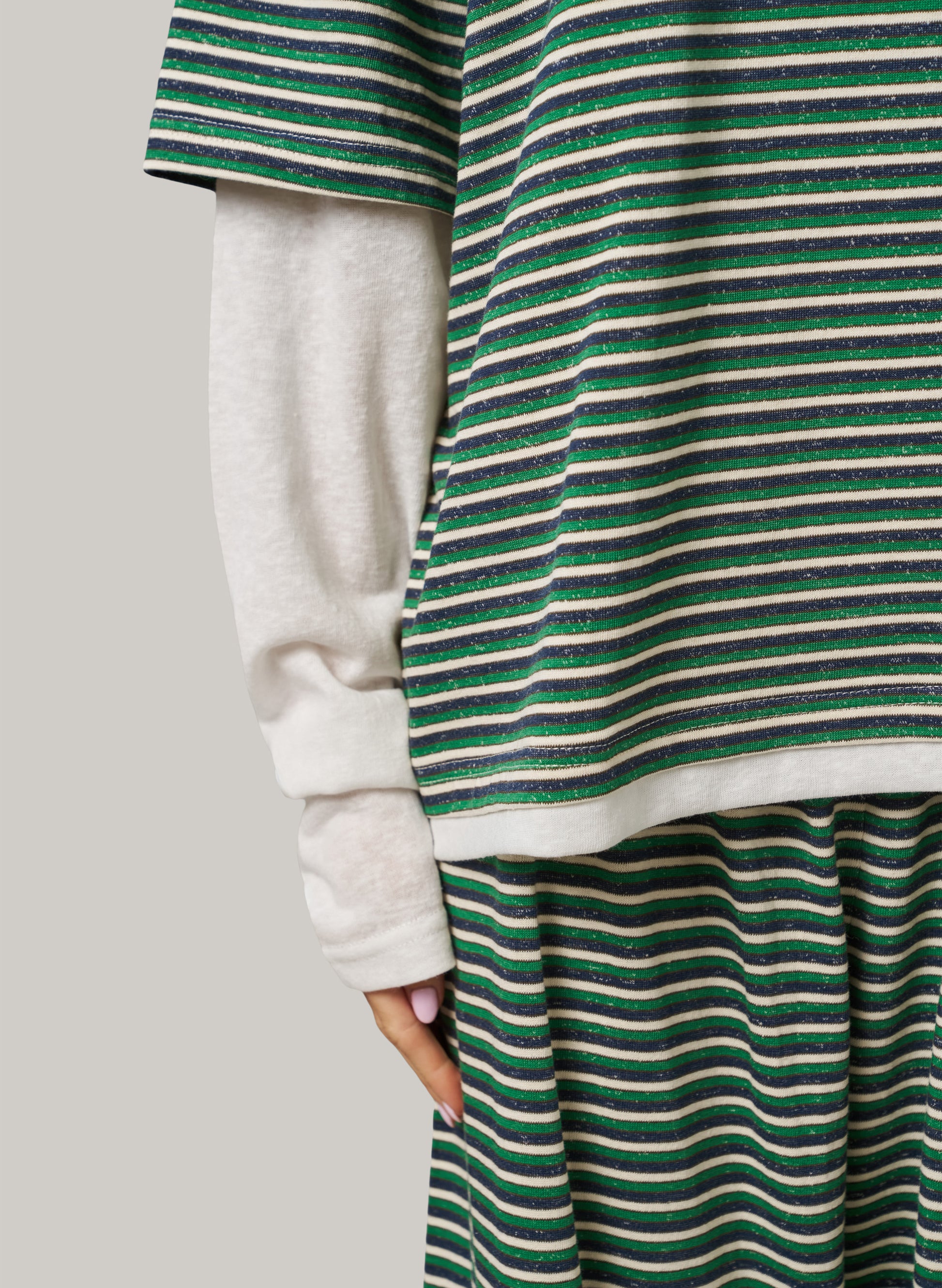 Person wearing a green and white striped dress with a plain background