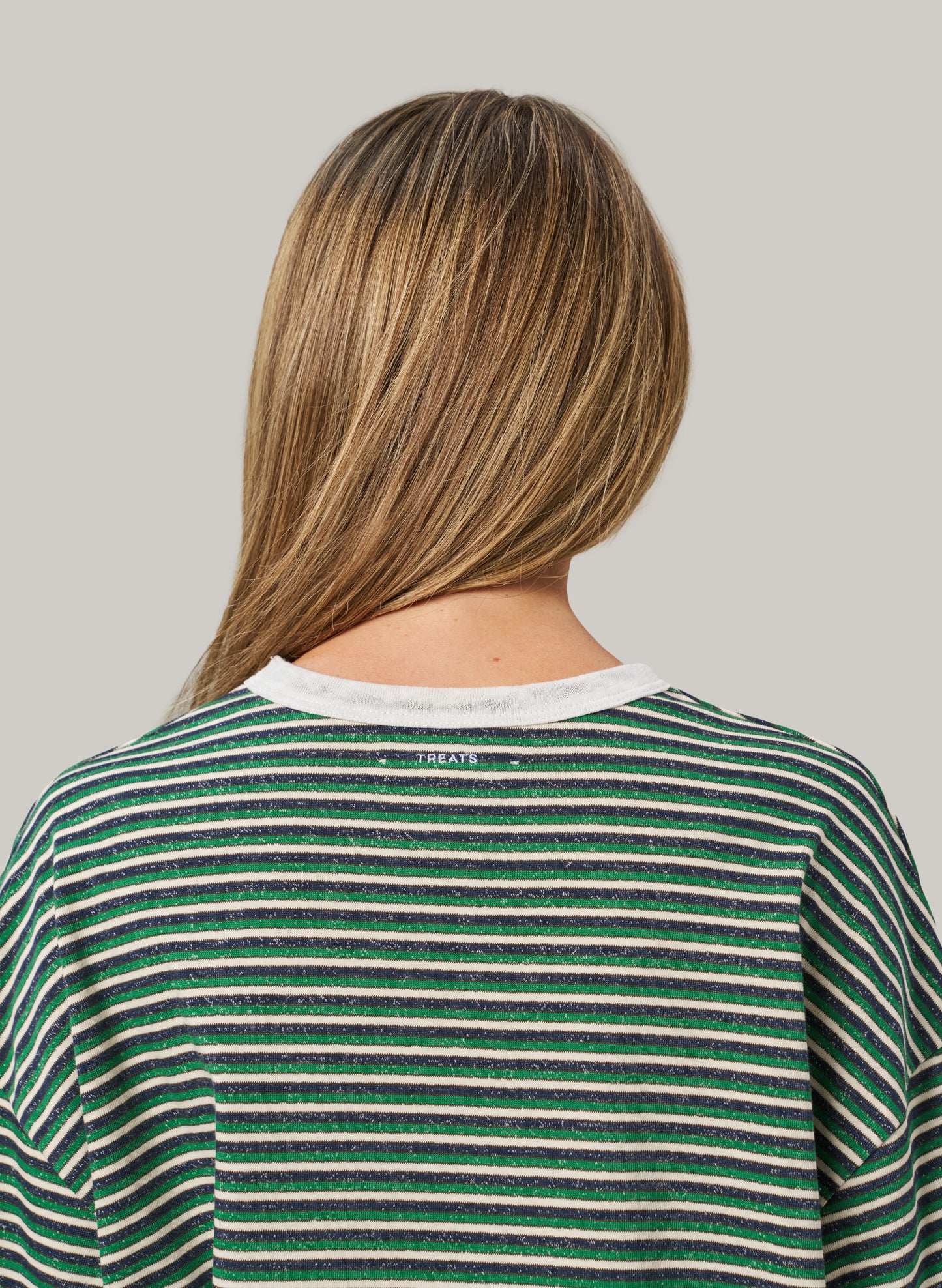 Person wearing a green and white striped shirt with 'Treat' branding on a plain background