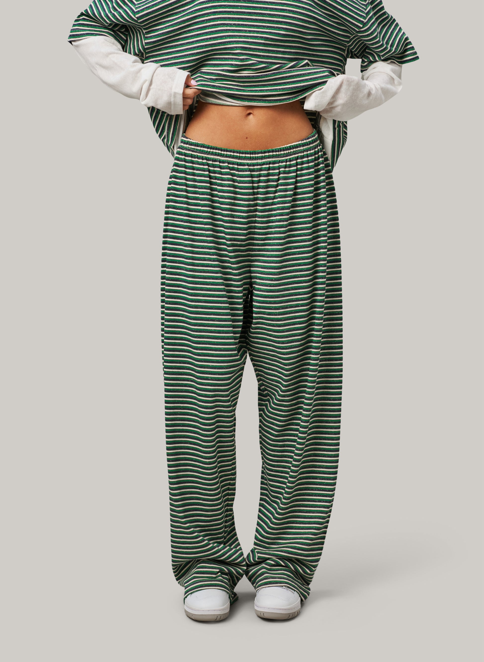 Person wearing green and white striped pants on a plain background