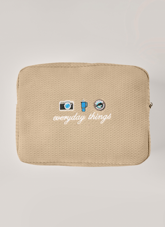 Beige pouch with 'everyday things' text and icons on a light gray background