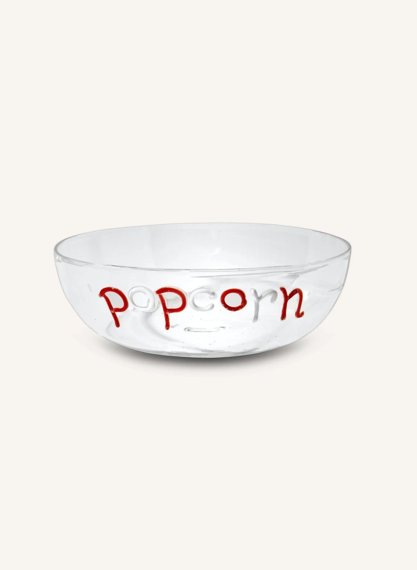 A clear glass popcorn bowl with the word 'popcorn' written in red lowercase letters on the front, set against a solid off-white background.