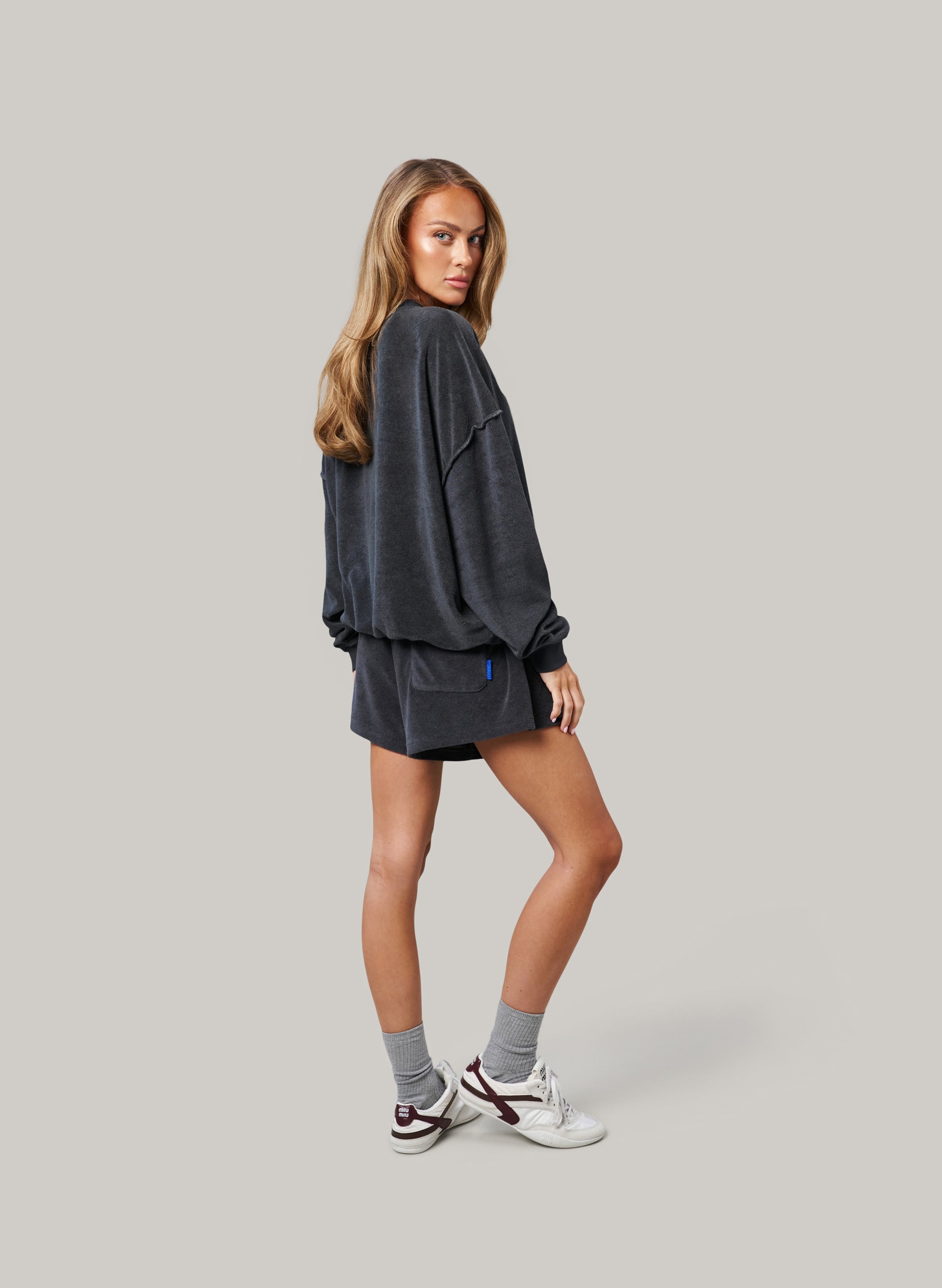 Woman wearing a dark gray outfit with shorts on a plain background