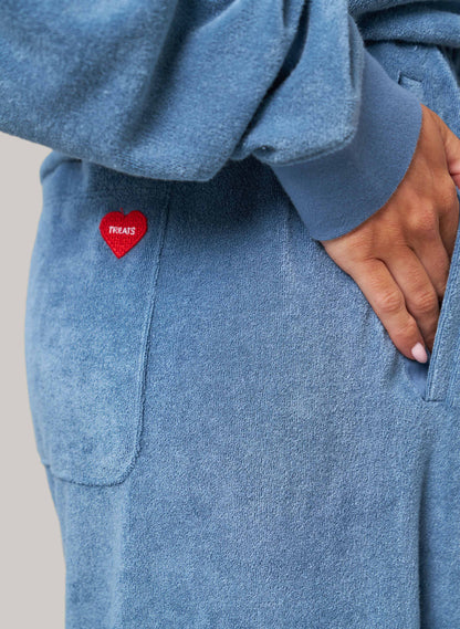 Blue fleece hoodie with a red heart-shaped tag on a gray background