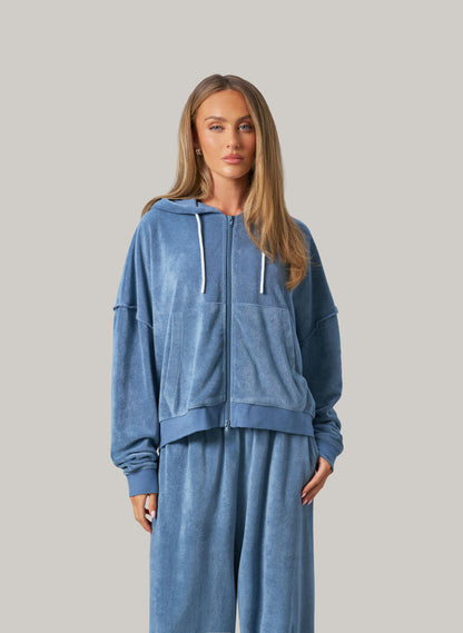 Woman wearing a blue tracksuit against a gray background