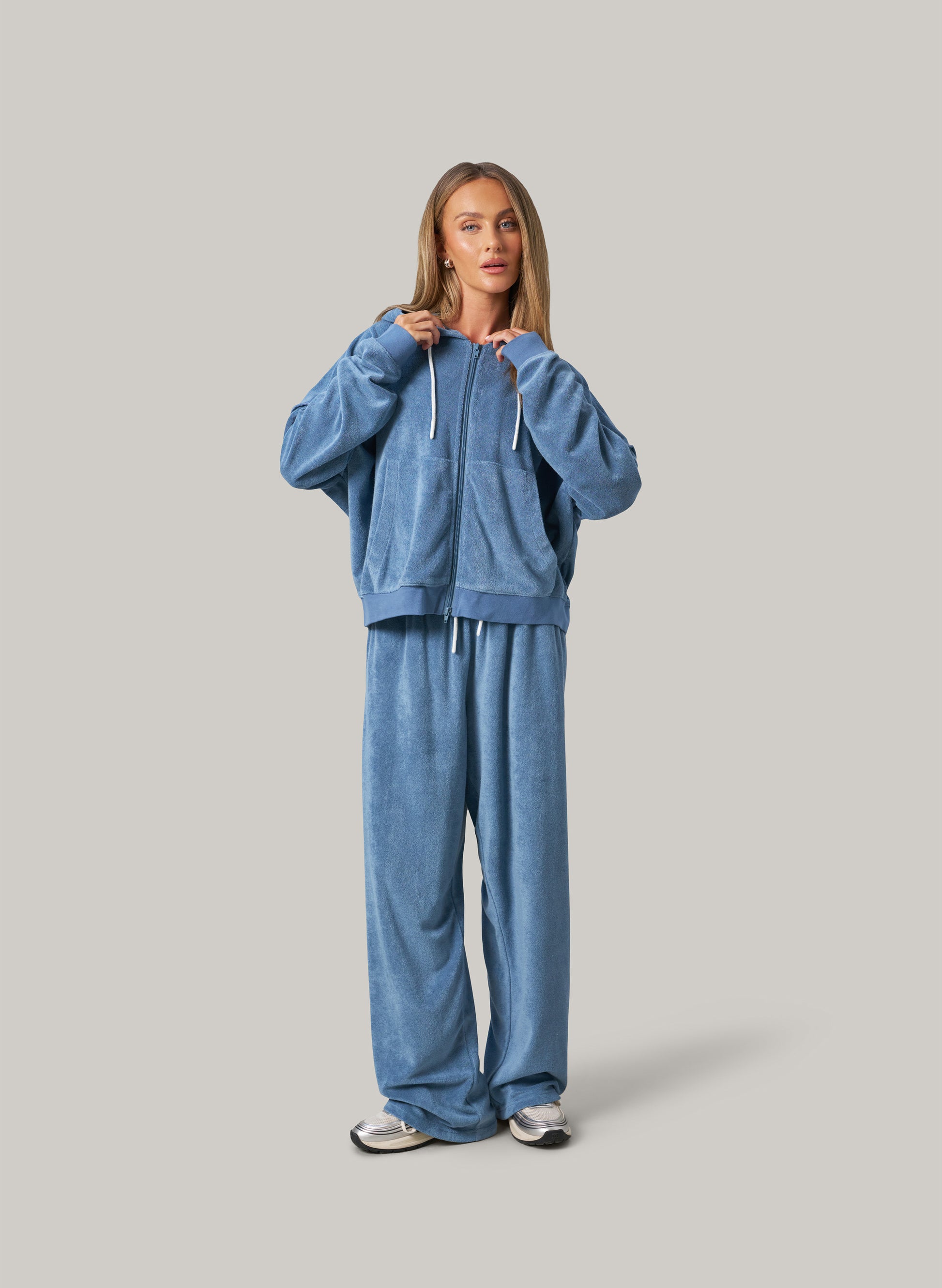 Person wearing a blue tracksuit on a grey background