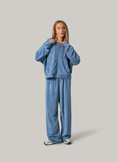 Person wearing a blue tracksuit on a grey background