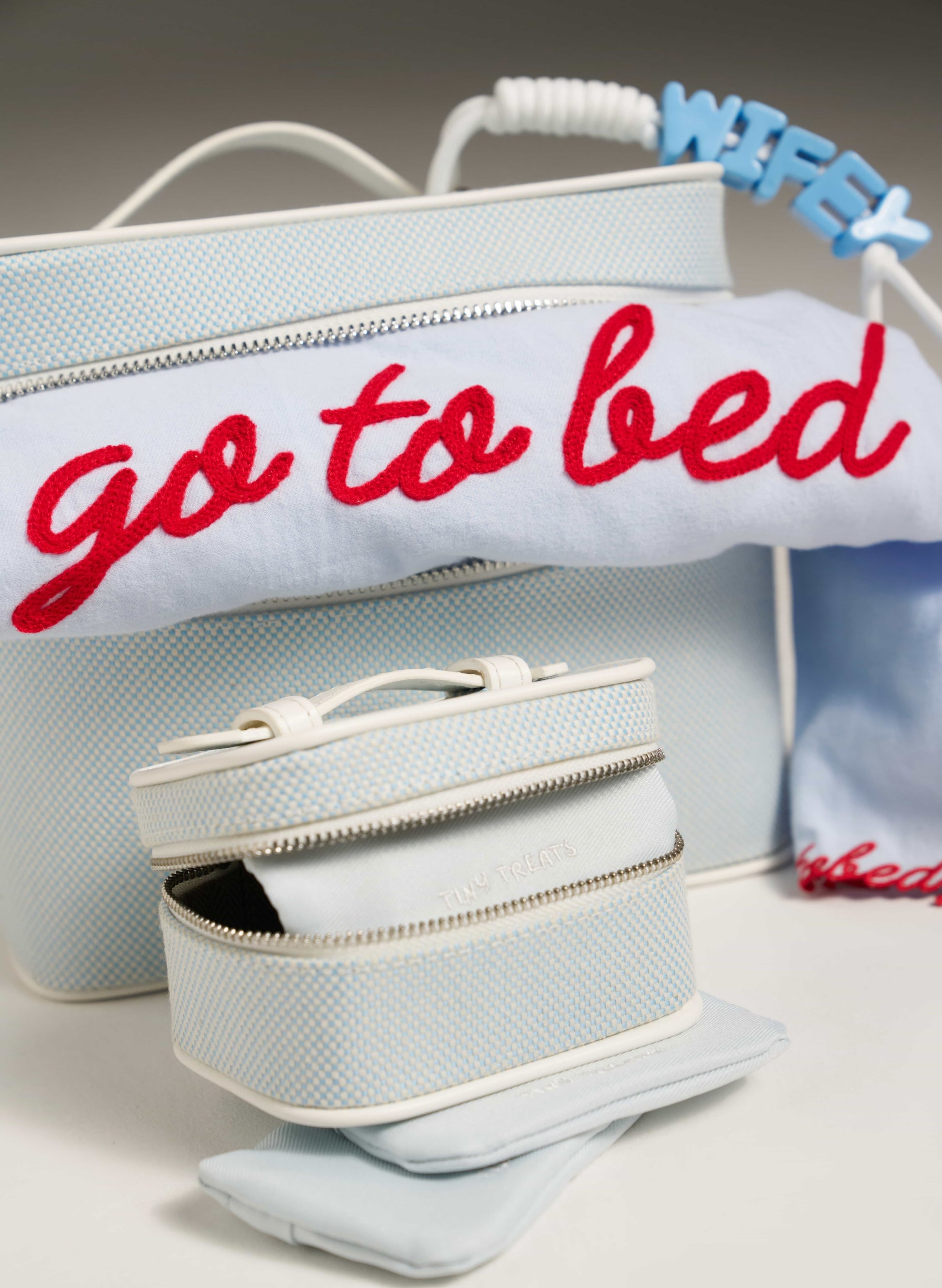 Light blue bag with 'go to bed' text and a smaller matching pouch on a neutral background
