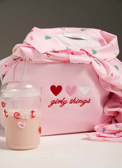 Pink bag with 'hearts girly things' text, surrounded by pink items on a gray background