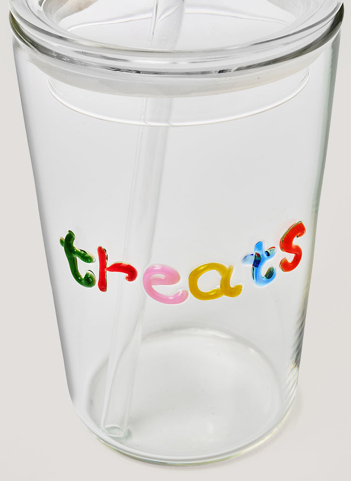 Clear glass tumbler with colorful letters spelling 'threats' on a white background