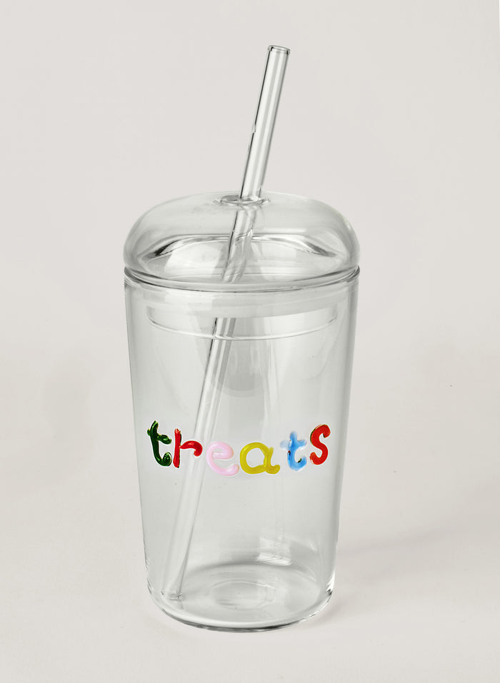 Clear tumbler with colorful letters 'treats' and a straw on a light grey background