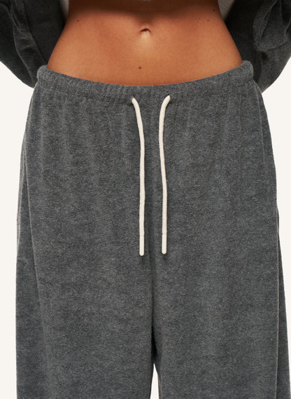 Close-up of a person wearing dark heather gray sweatpants with white drawstrings, cropped from the lower torso to upper thighs against a plain light background.