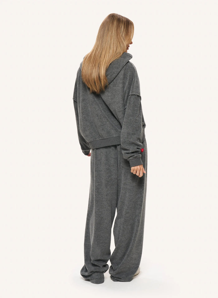 A woman shown from the back wearing a matching dark gray hooded sweatshirt and wide-leg sweatpants set, photographed against a plain light background.