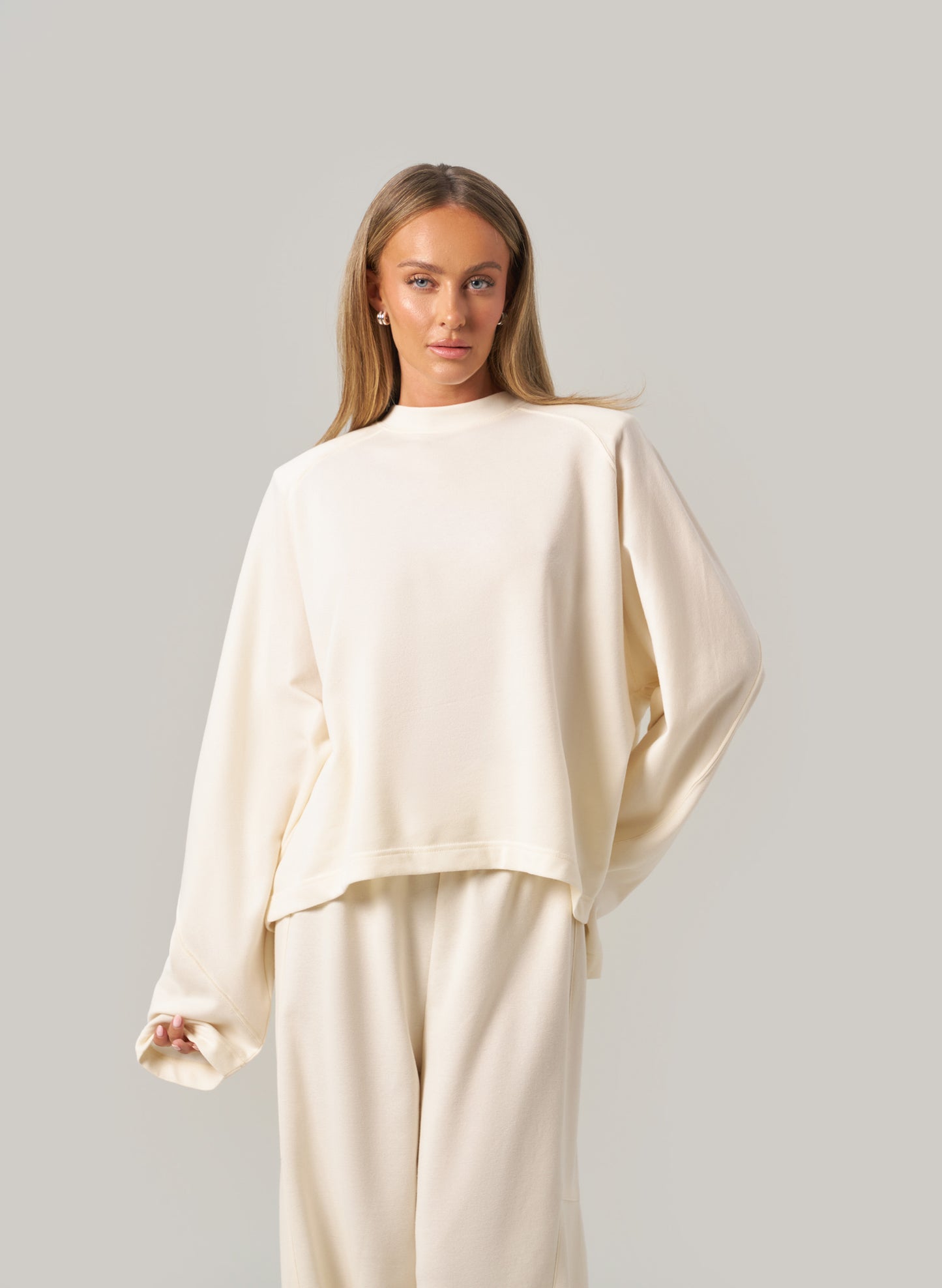 Woman wearing a cream-coloured outfit against a plain background