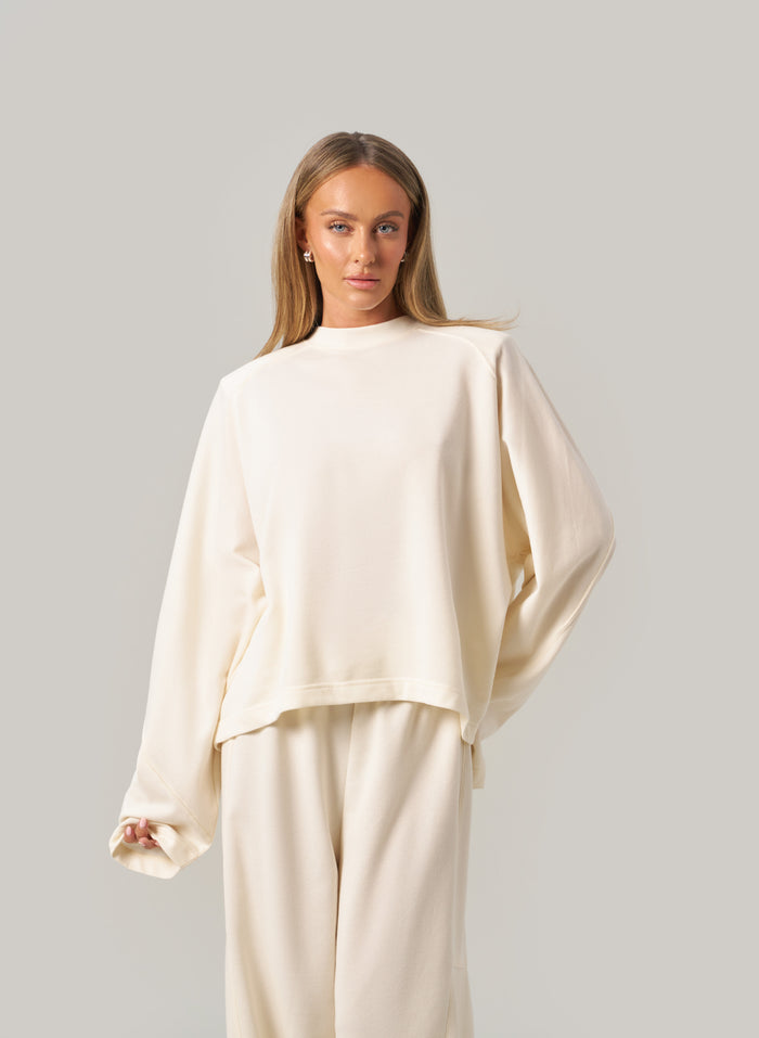 Woman wearing a cream-coloured outfit against a plain background