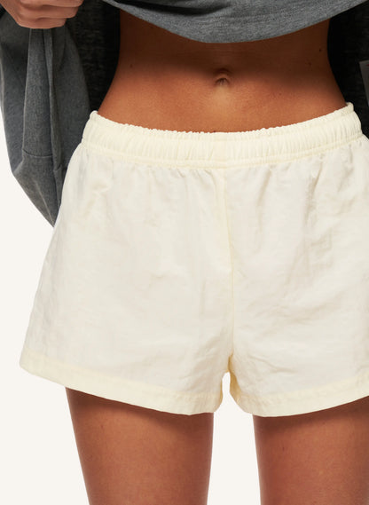 A close-up of a person wearing lemon linen shorts with an elastic waistband, paired with a gray sweatshirt.