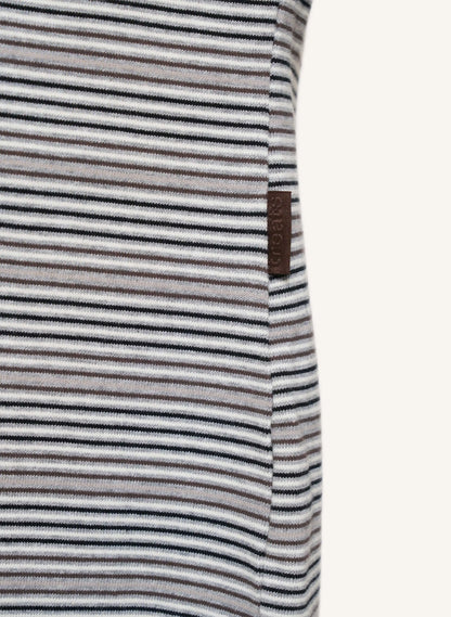 Close-up of a striped garment with thin horizontal black, gray, and white stripes, featuring a small brown brand tag on the side.