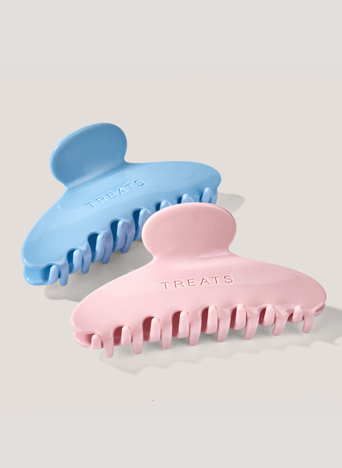 Two hair clips, one blue and one pink, on a light gray background.