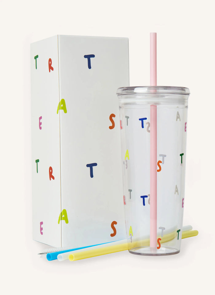 A clear tumbler with a pink straw against a solid off-white background.