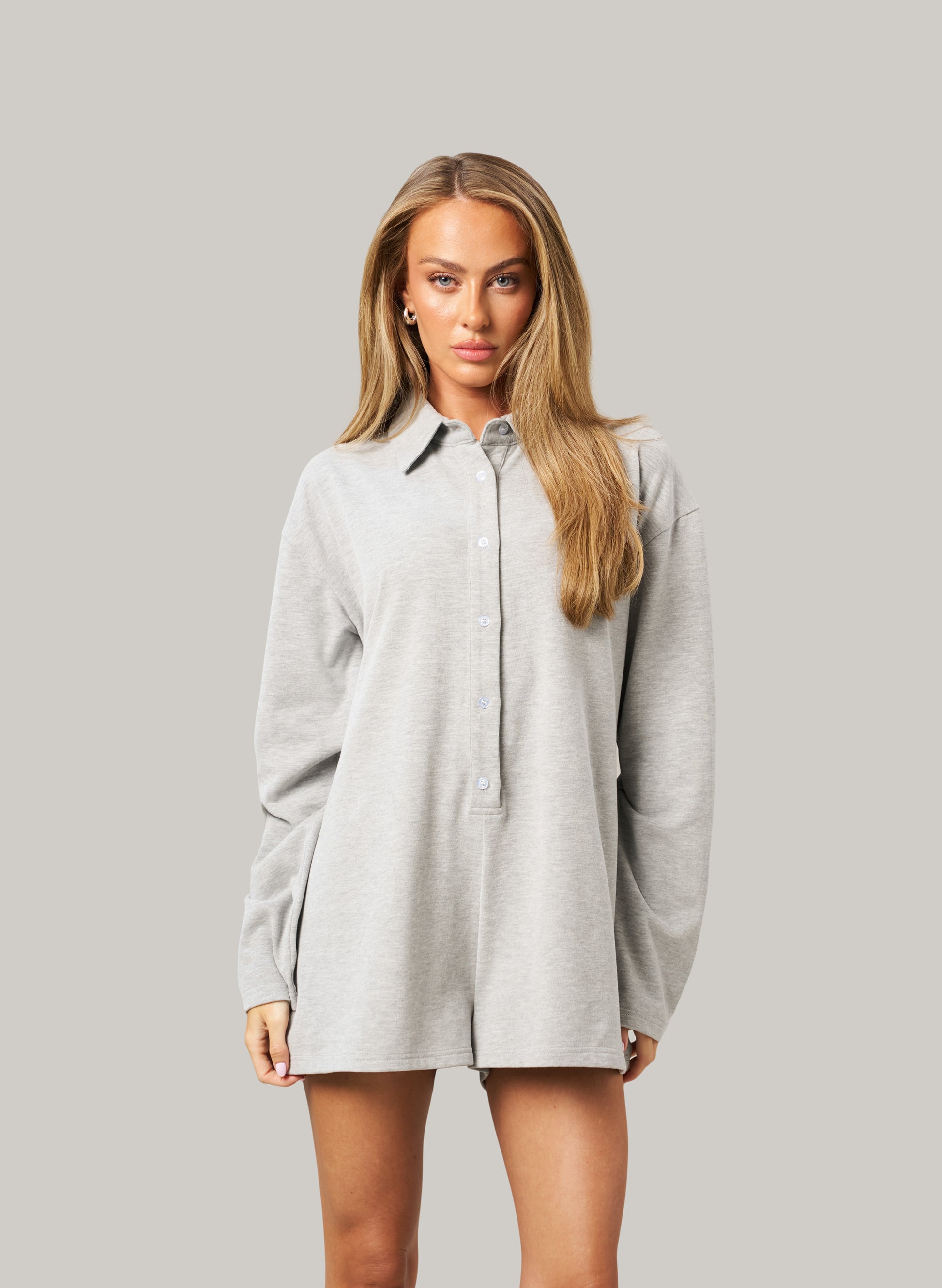 Woman wearing a grey romper against a plain background