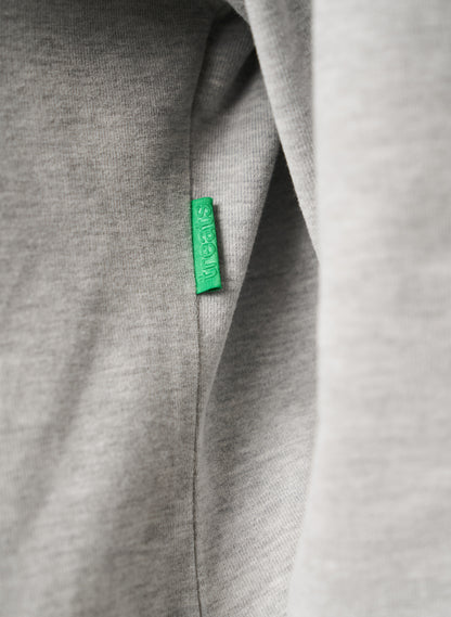 Close-up of a gray fabric with a green tag on a plain background